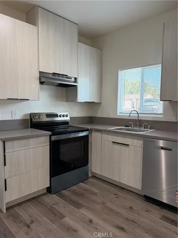a white kitchen with granite countertop a stove a sink and a microwave