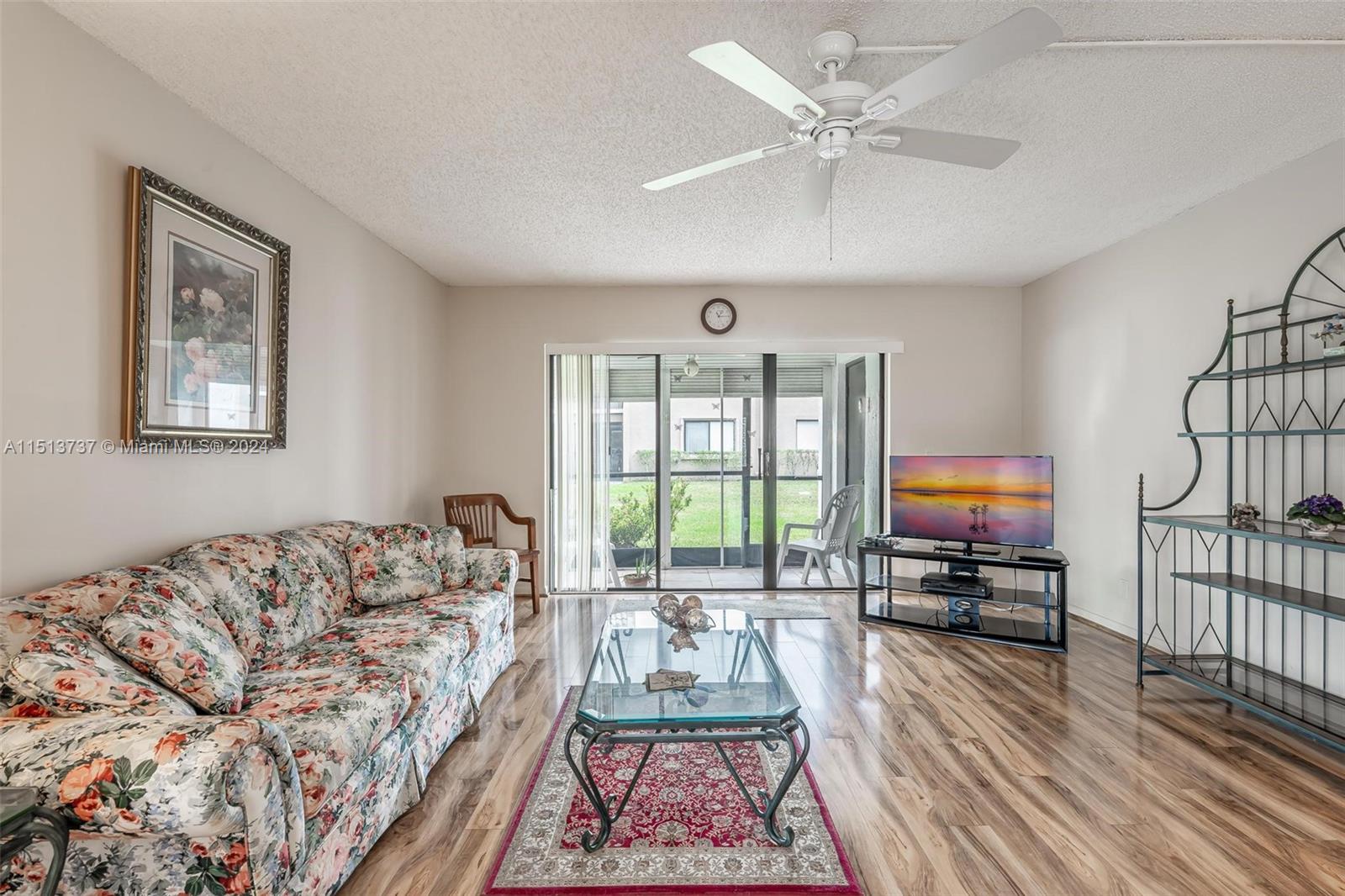 304 Racquet Club Road, Unit 101 Weston, FL 33326 - Photo 11 of 29 a living room with furniture a flat screen tv and a floor to ceiling window