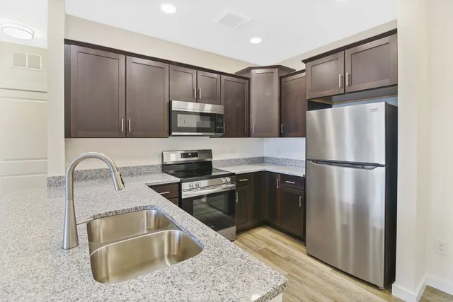 a kitchen with granite countertop a refrigerator sink and microwave
