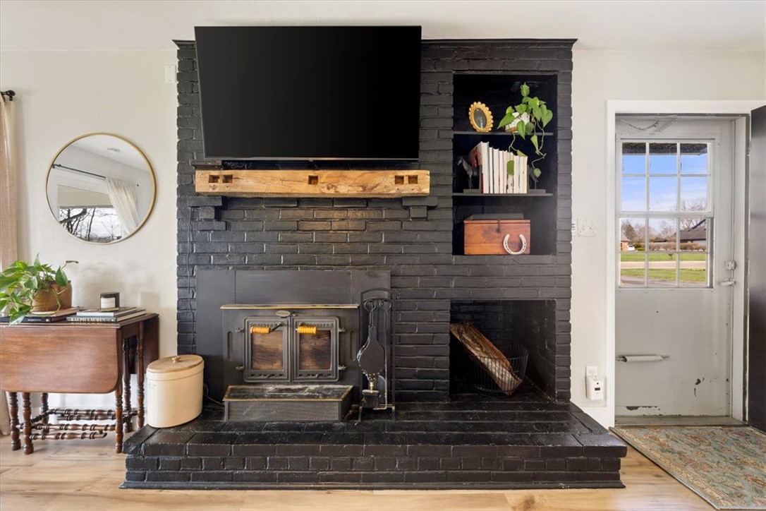 9555 Clyo Road Dayton, OH 45458 - Photo 9 of 31 This living area features a brick fireplace with a wood-burning stove and a charming built-in bookshelf.