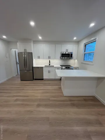 a large white kitchen with wooden floors stainless steel appliances and cabinets