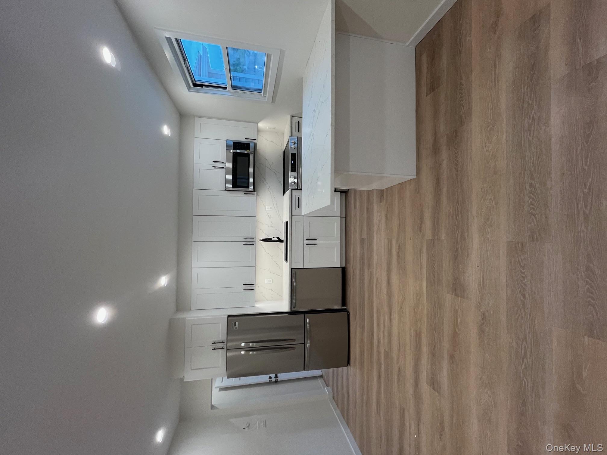 12 Backman Avenue, Unit 1 Ellenville, NY 12428 - Photo 4 of 9 a large white kitchen with wooden floors stainless steel appliances and cabinets