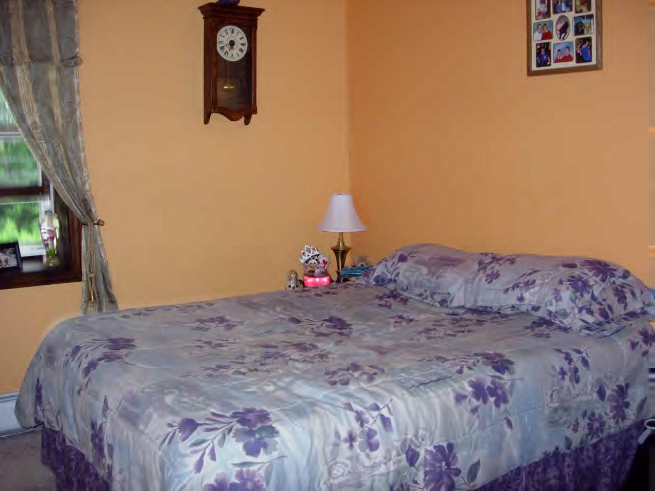 259 NW Road Westhampton, MA 01027 - Photo 7 of 10 a bed sitting in a bedroom next to a window with a flat tv screen and a lamp on table