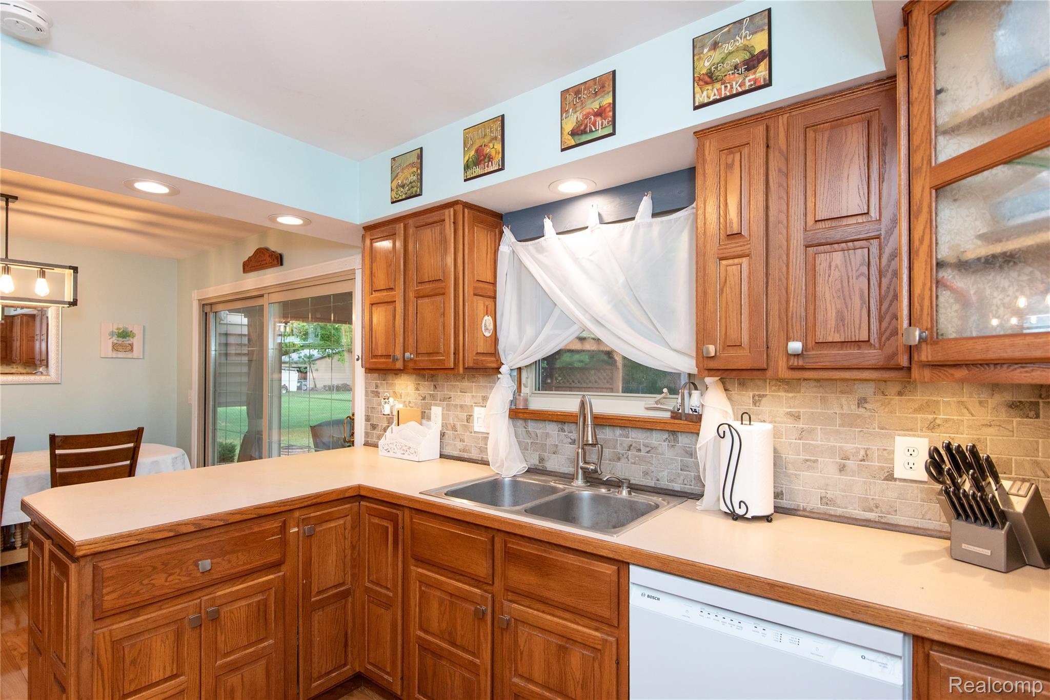 4395 Regency Road Swartz Creek, MI 48473 - Photo 23 of 67 Wood cabinetry with paneled fronts, tile backsplash, built-in dishwasher, and stainless steel double basin sink