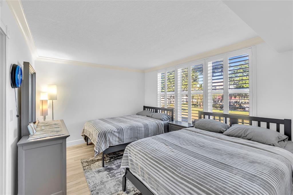 3150 Northeast 48th Court, Unit 204 Lighthouse Point, FL 33064 - Photo 18 of 28 a bedroom with two beds and a large window