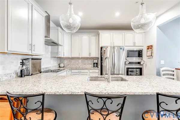 a kitchen with granite countertop kitchen island stainless steel appliances a sink and a refrigerator