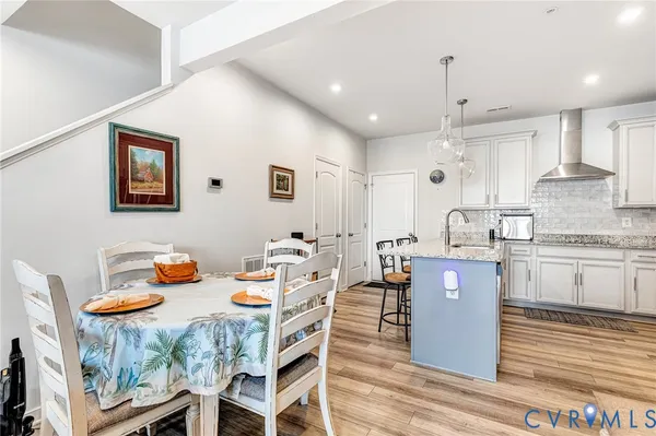 a kitchen with stainless steel appliances kitchen island granite countertop a table chairs and a refrigerator