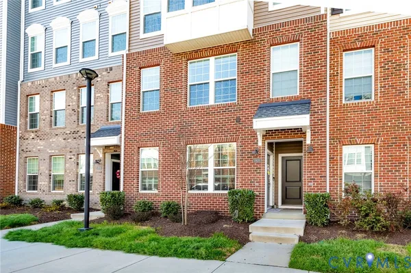 a front view of a brick building with many windows and yard