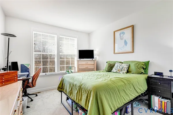 a bedroom with a bed a computer on the desk and a chair