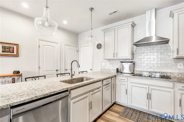 a kitchen with a sink dishwasher and white cabinets with wooden floor