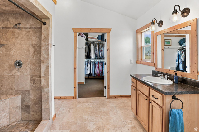 715 Ranch Loop Road Preston, ID 83263 - Photo 27 of 77 Primary Suite Bathroom featuring a walk-in shower with tile surround and integrated bench, wood-finish vanity with countertop and integrated sink, framed mirror, and wood-finish trim throughout