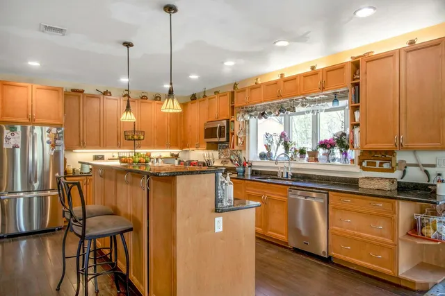 a kitchen with stainless steel appliances granite countertop a sink a stove and a refrigerator