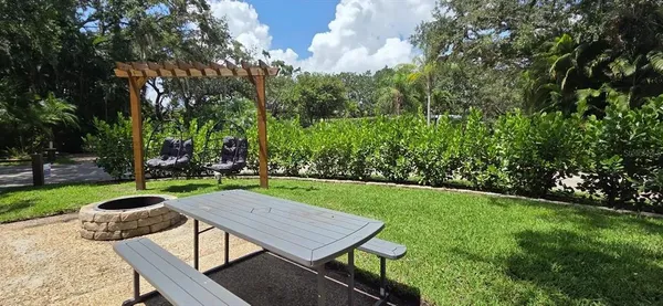a view of a backyard with table and chairs potted plants and large tree