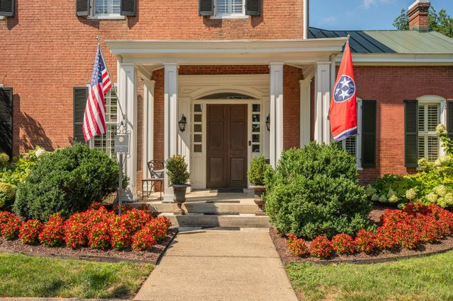 a kitchen with granite countertop a stove a sink a refrigerator wooden floor and cabinets