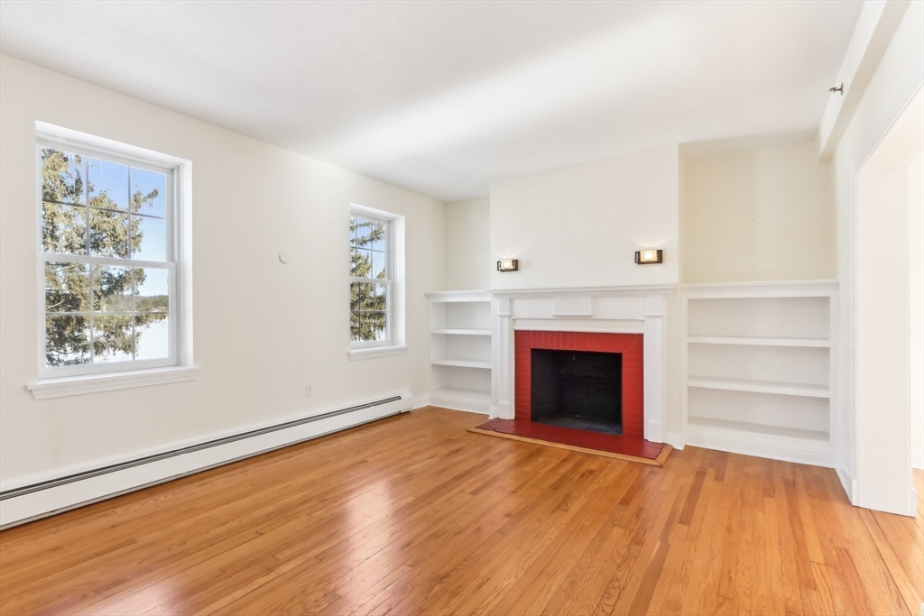 27 Elm Road, Unit D Devens, MA 01434 - Photo 5 of 31 a view of an empty room with wooden floor fireplace and a window