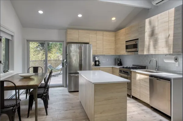 a kitchen with stainless steel appliances granite countertop table chairs sink refrigerator and cabinets