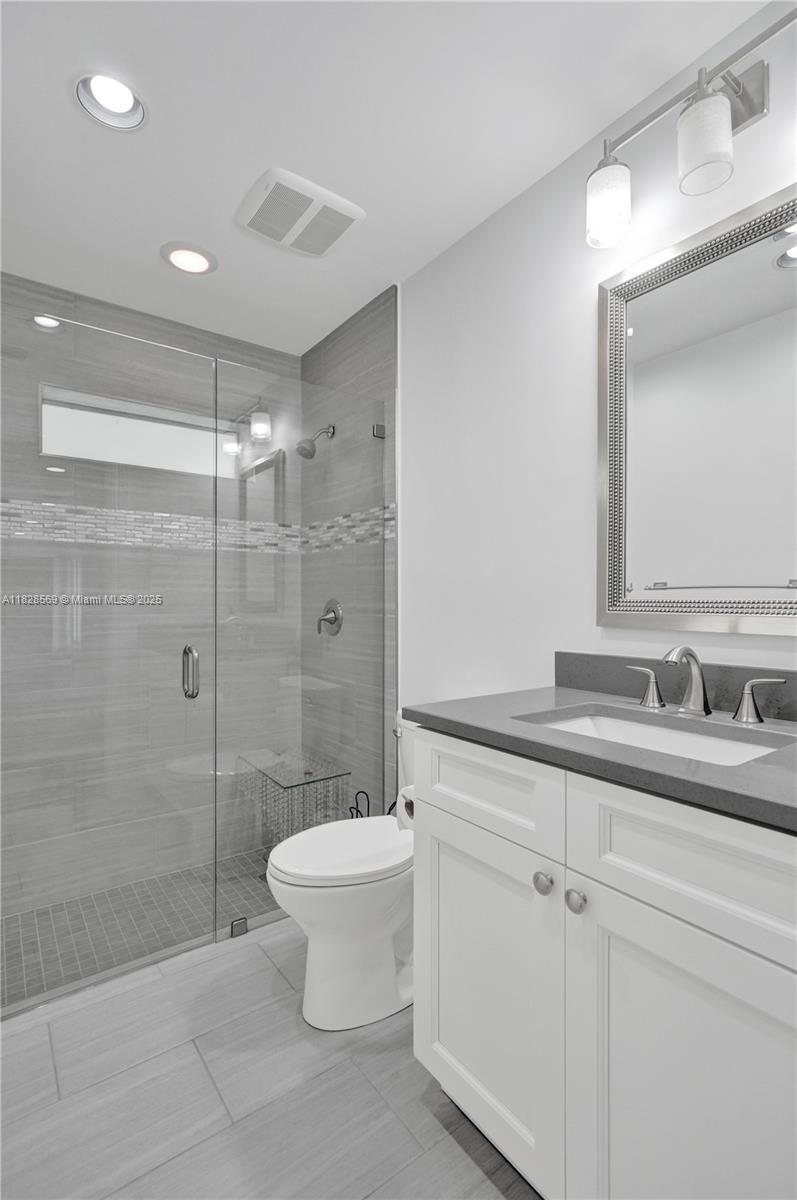 5854 Pinebrook Drive Boca Raton, FL 33433 - Photo 42 of 76 a bathroom with a granite countertop sink a toilet a mirror and shower