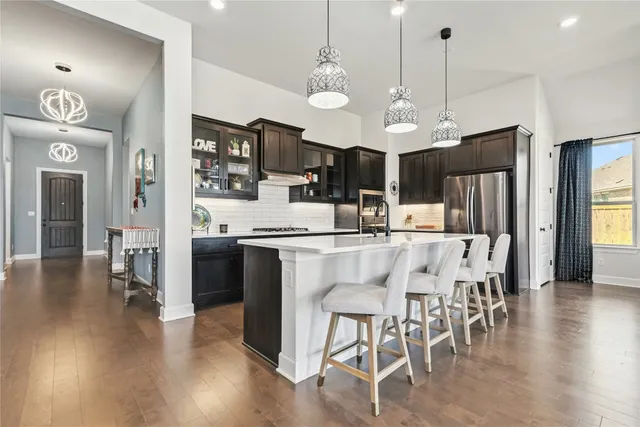 a kitchen with stainless steel appliances kitchen island granite countertop a refrigerator a stove a kitchen island with a dining table and chairs