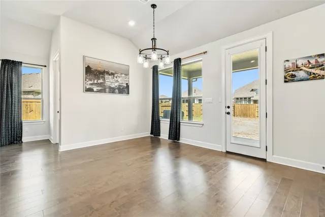 a view of a hallway with wooden floor and chandelier