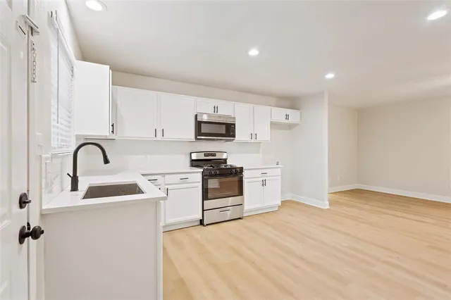 a kitchen with granite countertop white cabinets and stainless steel appliances