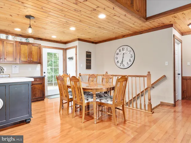 a kitchen with stainless steel appliances granite countertop a kitchen island a table chairs and a refrigerator