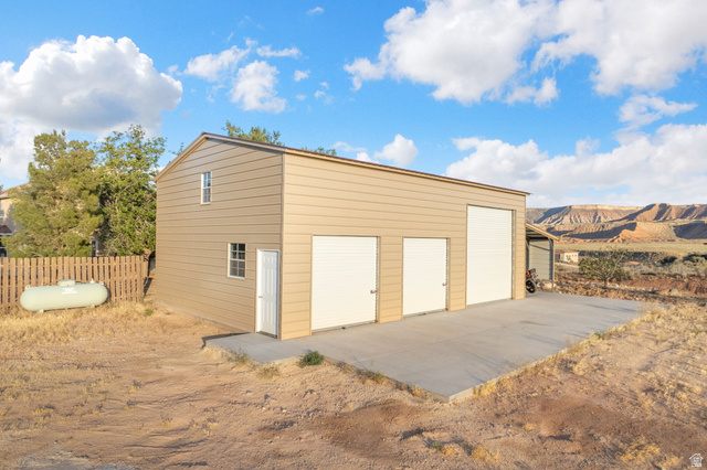 1440 West 100 South Virgin, UT 84779 - Photo 39 of 45 Two-story detached structure featuring three white roll-up doors, a pedestrian entry door, and a second-story window