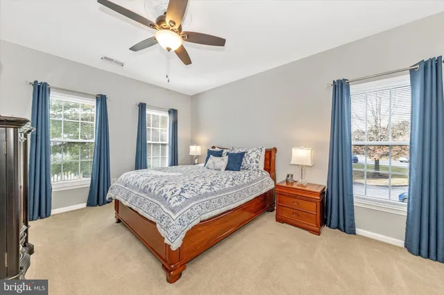 a spacious bedroom with a large bed and a chandelier fan