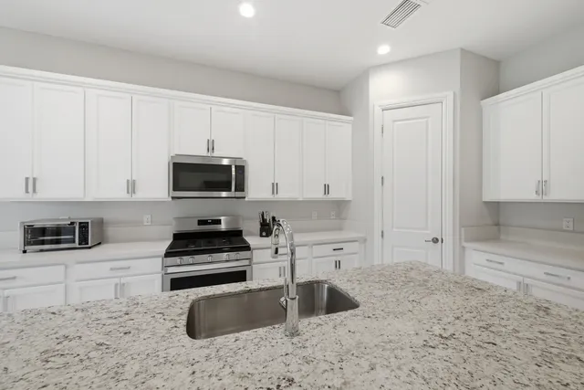 a kitchen with granite countertop a sink a stove and cabinets