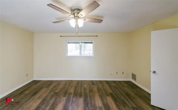 an empty room with wooden floor chandelier fan and windows