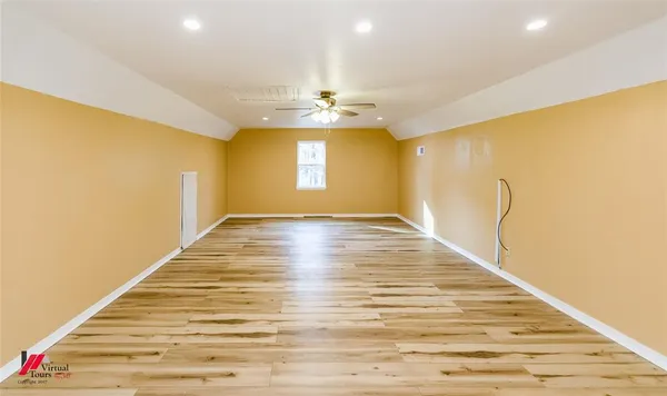 a view of an empty room with window and wooden floor