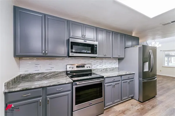 a kitchen with granite countertop wooden cabinets stainless steel appliances and a counter space