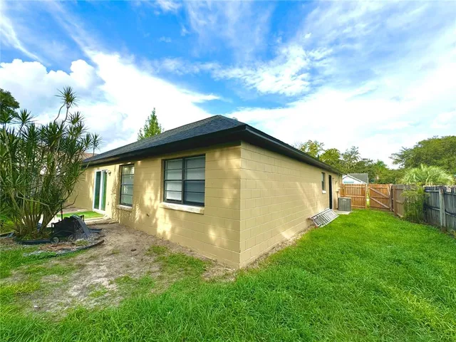 a view of a backyard with large trees and wooden fence