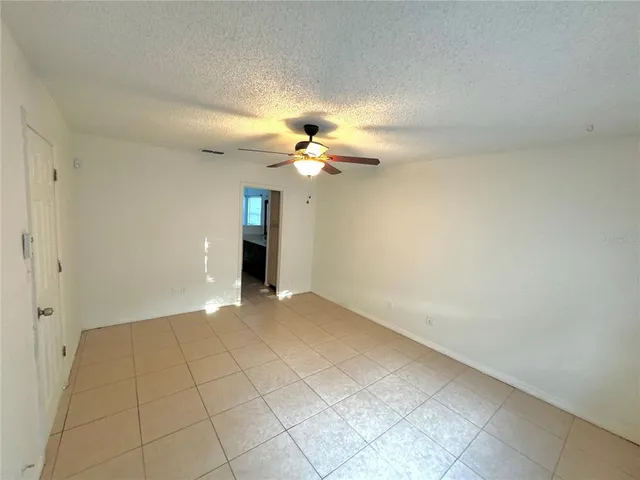 a view of an empty room with a chandelier fan and a window