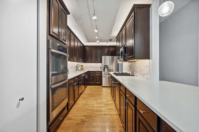 a kitchen with stainless steel appliances granite countertop lots of counter top space and wooden floor