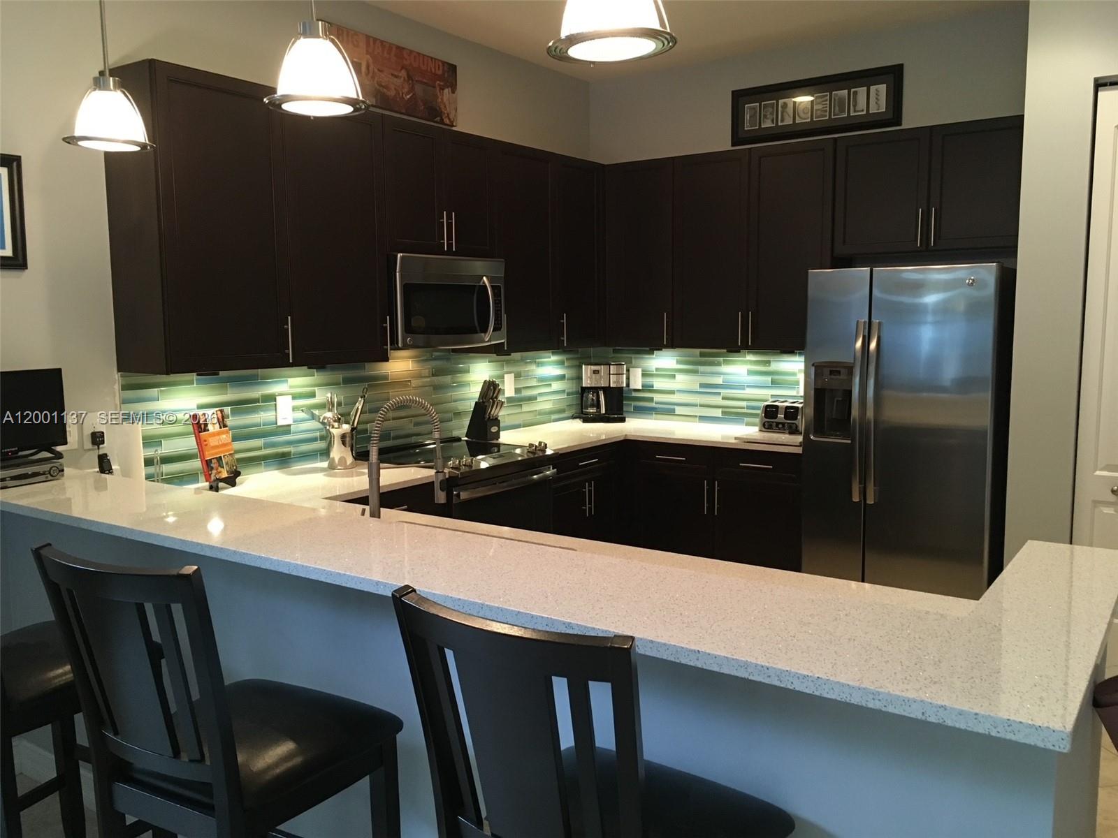 184 West Bay Cedar Circle Jupiter, FL 33458 - Photo 9 of 49 a kitchen with stainless steel appliances a sink a stove a refrigerator a counter top space and cabinets
