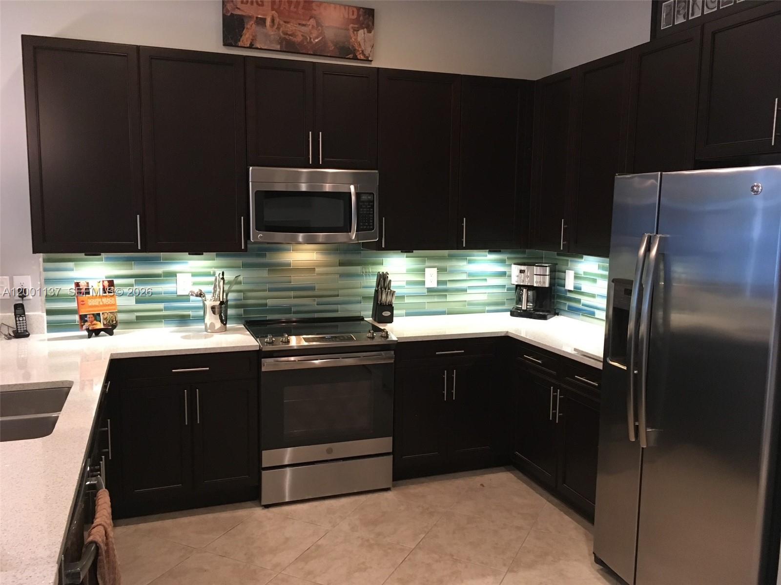 184 West Bay Cedar Circle Jupiter, FL 33458 - Photo 10 of 49 a kitchen with stainless steel appliances wooden cabinets and a sink