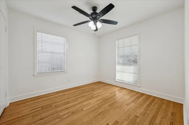 a view of empty room with wooden floor and fan