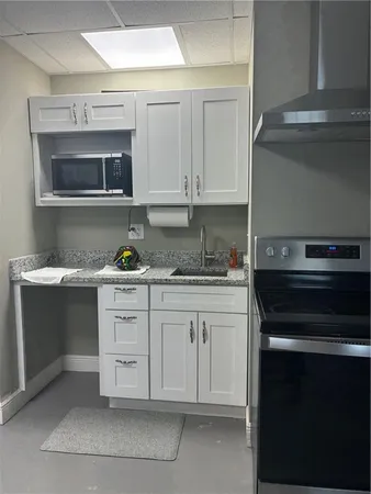 a kitchen with granite countertop white cabinets and stainless steel appliances