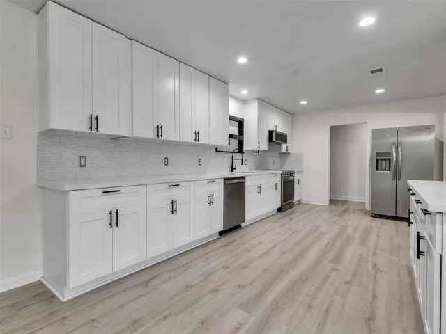 a large kitchen with stainless steel appliances granite countertop a lot of counter space and wooden floors