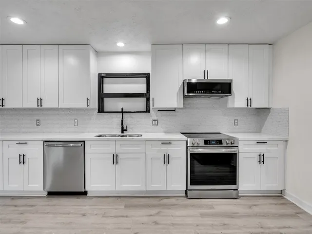a kitchen with stainless steel appliances granite countertop a stove a sink and a microwave