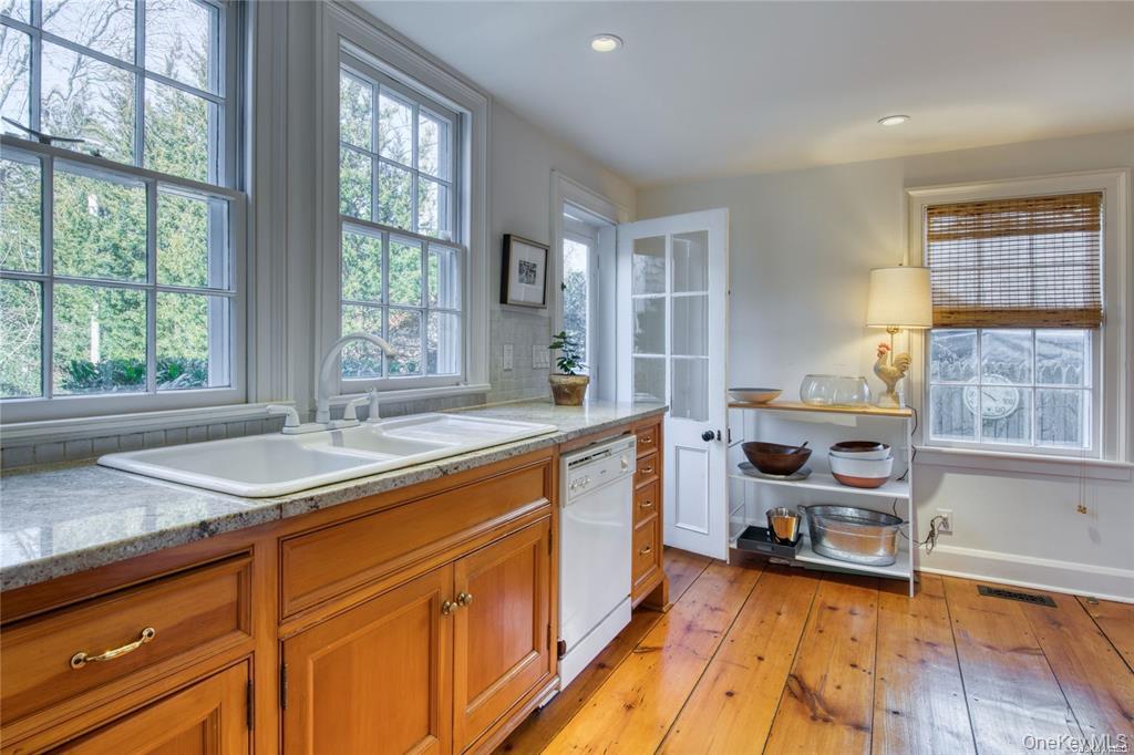 1800 Village Lane Orient, NY 11957 - Photo 7 of 12 Kitchen featuring brown cabinetry, light wood-type flooring, light stone counters, dishwasher, and recessed lighting