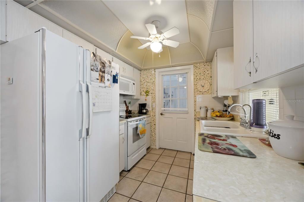 3801 Chinaberry Road Bradenton, FL 34208 - Photo 8 of 31 a kitchen with a refrigerator a stove top oven a chimney cabinets and a dining table