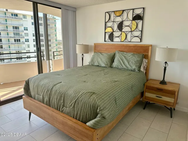 a bedroom with a bed a lamp and a large window with garden view