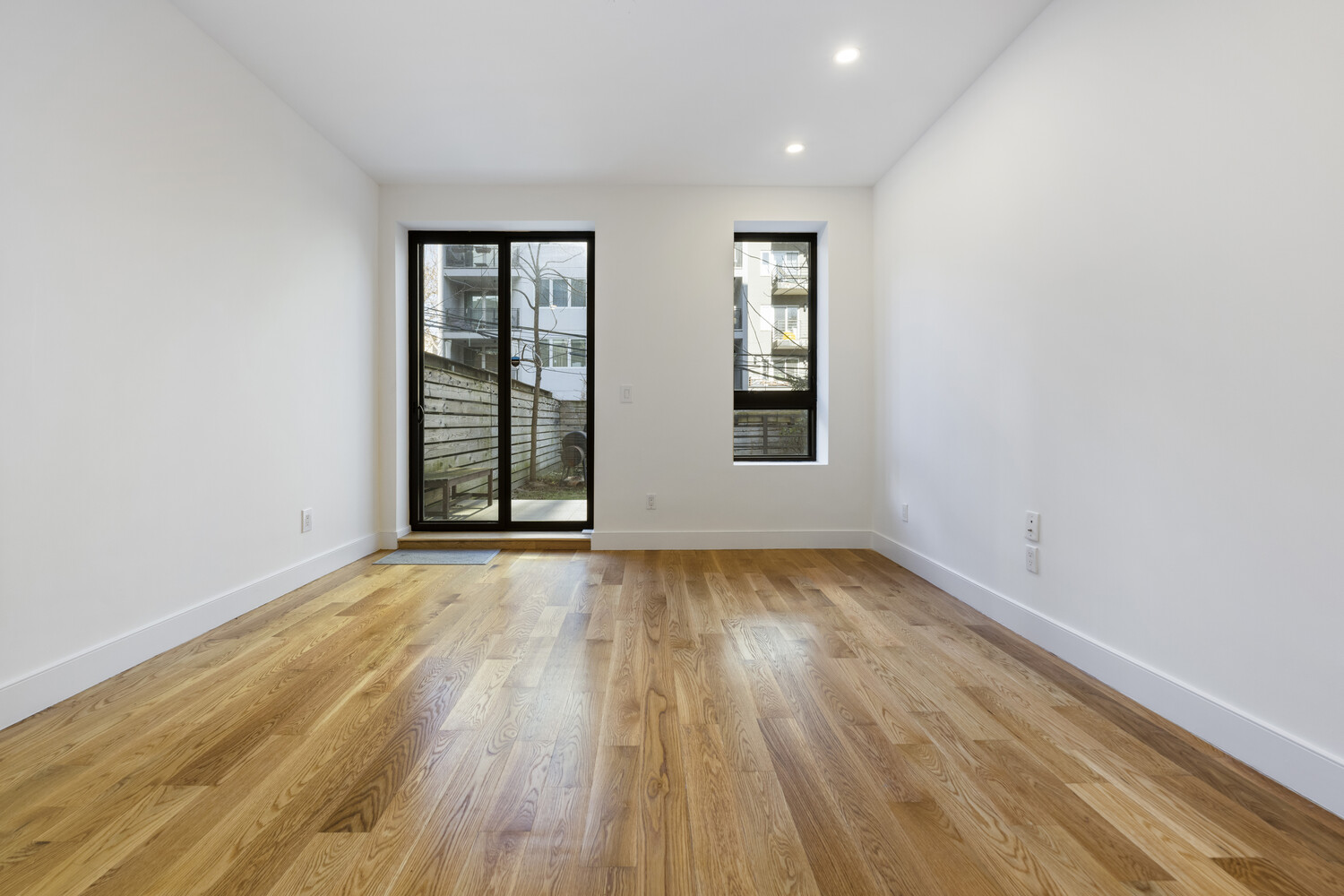79 Clay Street, Unit 1R Brooklyn, NY 11222 - Photo 9 of 11 an empty room with wooden floor and windows