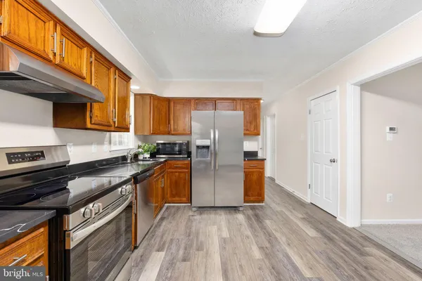 a kitchen with stainless steel appliances granite countertop a refrigerator stove and sink