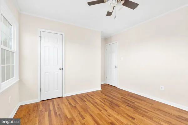 a view of empty room with wooden floor and fan