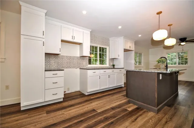 a large kitchen with kitchen island white cabinets and stainless steel appliances