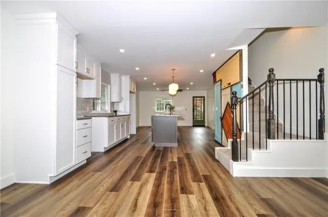 a view of a kitchen with kitchen island wooden floors stainless steel appliances and a window
