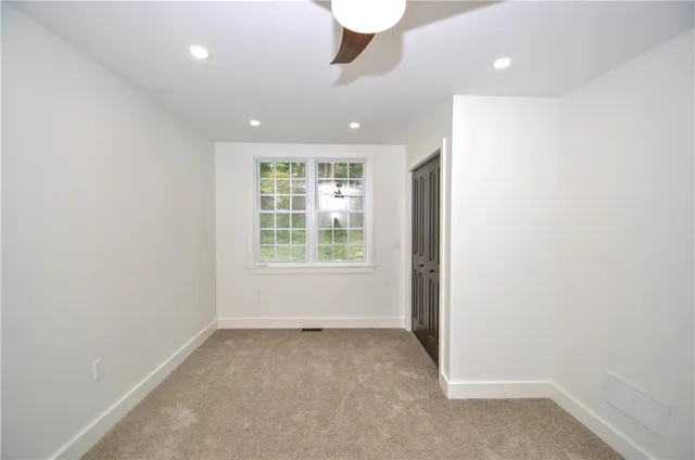 an empty room with windows and chandelier fan