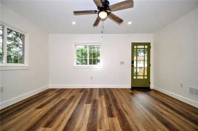 a view of an empty room with wooden floor and a window